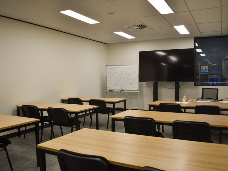 Aula con mesas y una pantalla grande